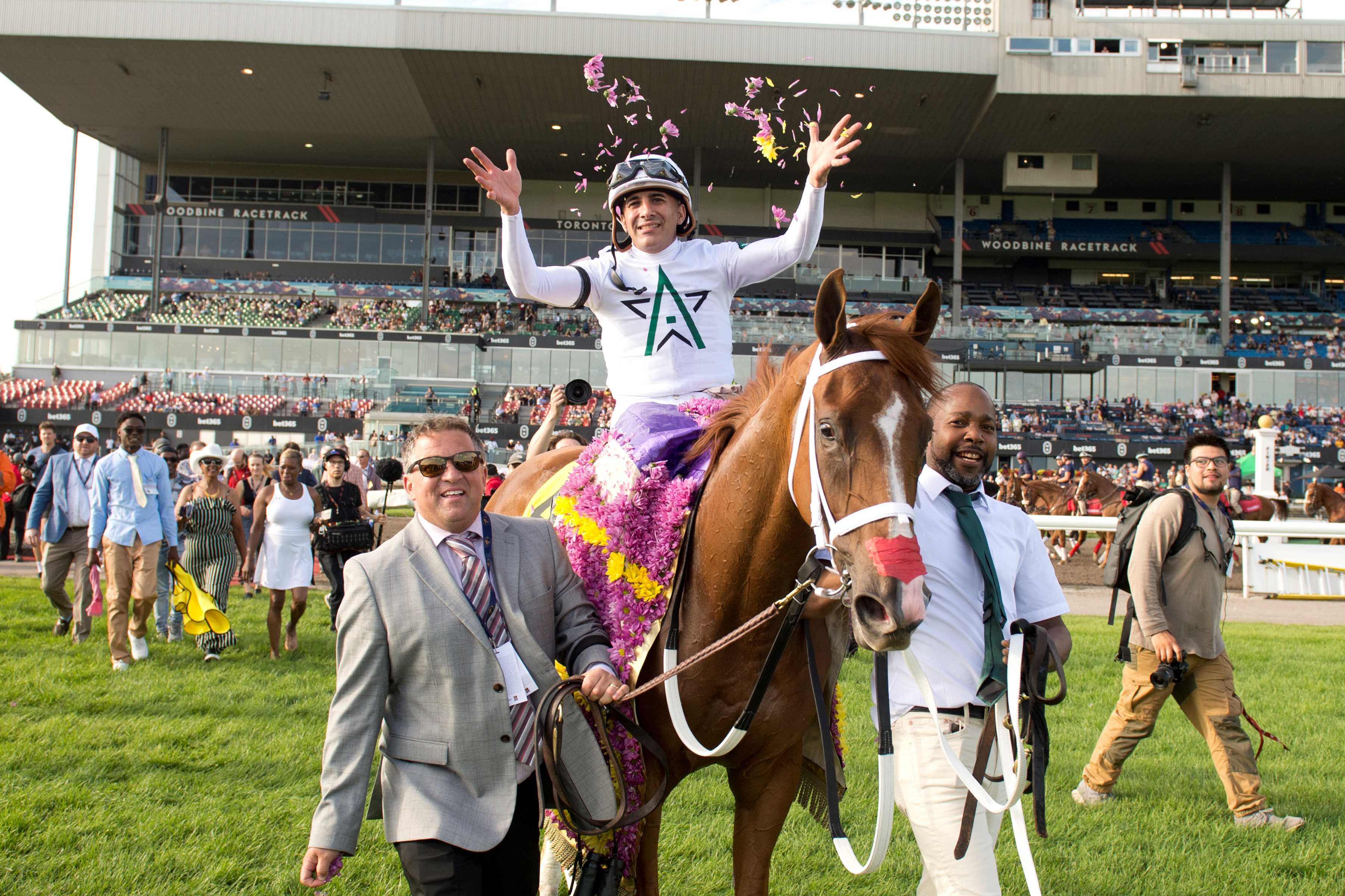 Caitlinhergrtness, trainer Kevin Attard, and jockey Rafael Hernandez walking to the Woodbine Winner's Circle after winning The 165th King's Plate (Michael Burns Photo) 