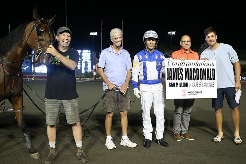 James MacDonald is congratulated by Bill McLinchey, Director of Standardbred Racing, and is joined by Dewitt This Moment's connections of Paul Ritchie, Jim Ritchie and Nick Ritchie. (New Image Media)
